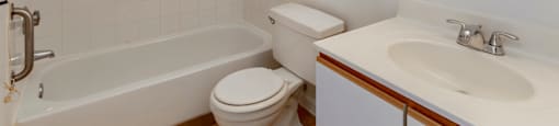 Bathroom with White Cabinets White Counters and White Bathtub and Shower with Handrails