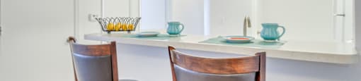 The breakfast bar opens to the kitchen. There are two barstools and place settings for two.