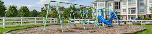 A playground with a green swing set and a blue slide.