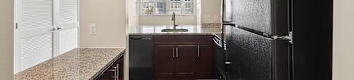 A kitchen with a black refrigerator and brown cabinets.