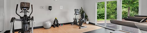 A home gym with a treadmill, exercise bike, and other equipment.