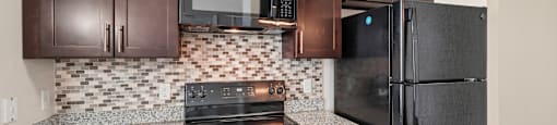 A kitchen with brown cabinets and a black refrigerator.