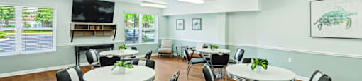 A room with tables and chairs and a painting on the wall.