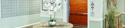 A room with a wooden floor and a round table with a vase of flowers on it.