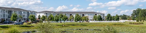 A field with a pond and a building in the background.