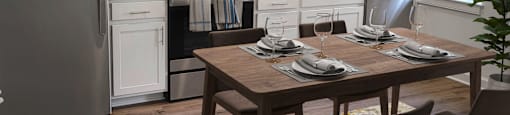 a kitchen with white cabinets and a wooden table in Sandy Spring Village