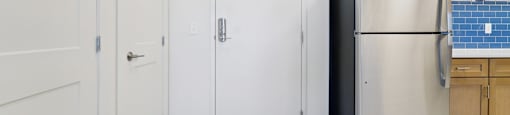 A kitchen with a refrigerator, cabinets, and a door.