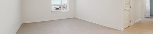 Empty room with a window and a wall-mounted air conditioner.