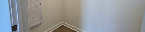 A white closet with a wooden floor and a white door.