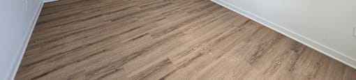 A room with a wooden floor and an air conditioner mounted on the wall.
