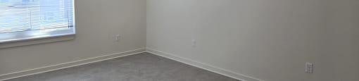 A room with a window and carpeted floor.
