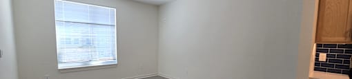 A room with a window and a kitchenette.