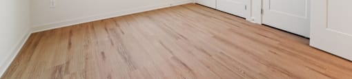 A room with wooden floors and white walls with a window.
