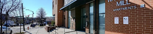 The image shows the exterior of Walbrook Mill Apartments with a clear blue sky in the background.