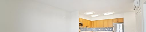 Empty room with wooden cabinets and a refrigerator.
