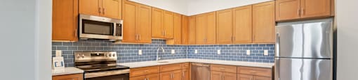 A kitchen with wooden cabinets and a blue tile backsplash.