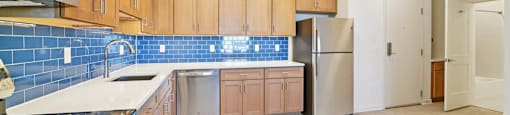 A kitchen with wooden cabinets and a blue tile backsplash.