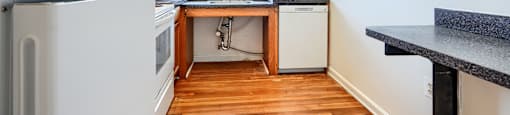A kitchen with a white fridge and wooden floors.