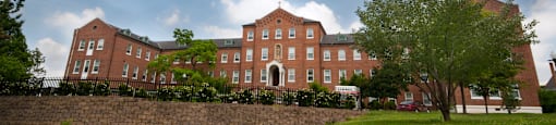 A large red brick building with a green lawn in front.