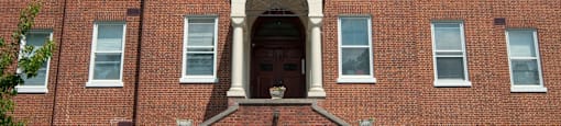 A red brick building with a statue on the front door.