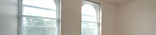 A room with two windows and wooden floors.