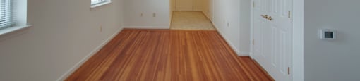 A long, empty hallway with wooden floors and white walls.