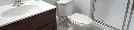 A bathroom with a toilet, sink, and mirror.