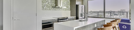 A kitchen with a white island and wooden chairs.
