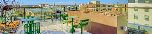 A patio with green chairs and a table with a view of the city.