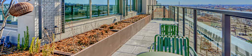 A balcony with a table and chairs overlooks a body of water.