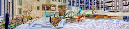 A wooden deck is surrounded by buildings.