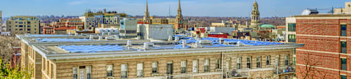 A view of a cityscape with a building in the foreground and a church spire in the background.