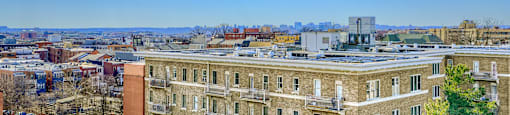 A large building with a flat roof is surrounded by other buildings.