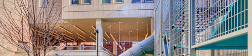 A playground with a green slide and a grey wall.