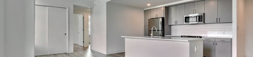 A modern kitchen with a white island and stainless steel appliances.