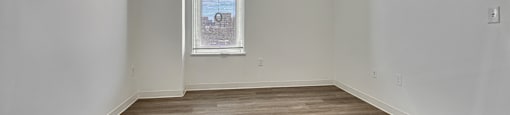 Empty room with a window and wooden flooring.