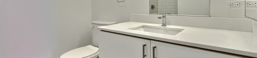 A white bathroom with a toilet, sink, and mirror.