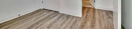 A room with a white door and a wooden floor.