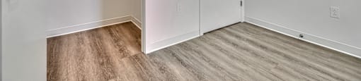 A white door is open to a hallway with a wood floor.