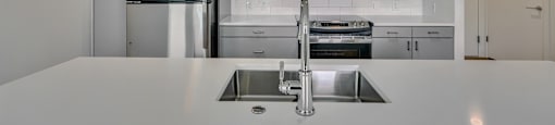 A modern kitchen with a stainless steel sink and refrigerator.