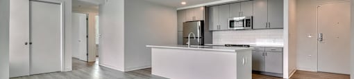 A modern kitchen with a white island and wooden floors.