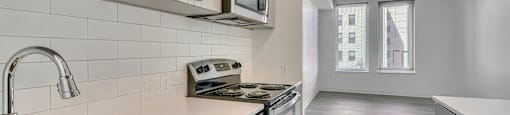 A modern kitchen with a stainless steel sink and white cabinets.