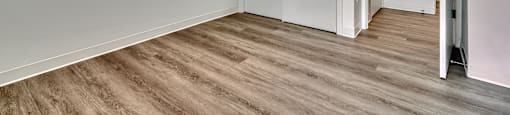 A room with white walls and wooden flooring with two doors.