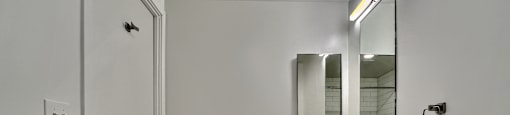 A white bathroom with a sink, mirror, and toilet.