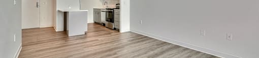 A spacious kitchen with white cabinets and a wooden floor.