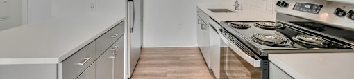 A modern kitchen with white appliances and wooden floors.