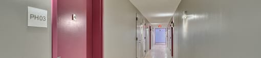 A long hallway with a pink door and a sign that says "PH03".