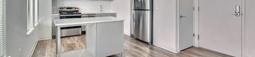 A modern kitchen with a stainless steel refrigerator and wooden flooring.