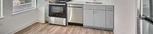 A modern kitchen with stainless steel appliances and wooden flooring.