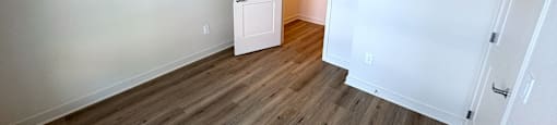 A room with a white door and wooden flooring.
